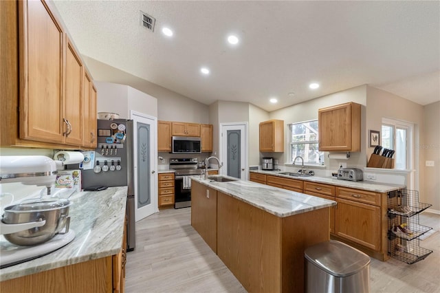 kitchen with a kitchen island with sink, sink, light hardwood / wood-style floors, and appliances with stainless steel finishes