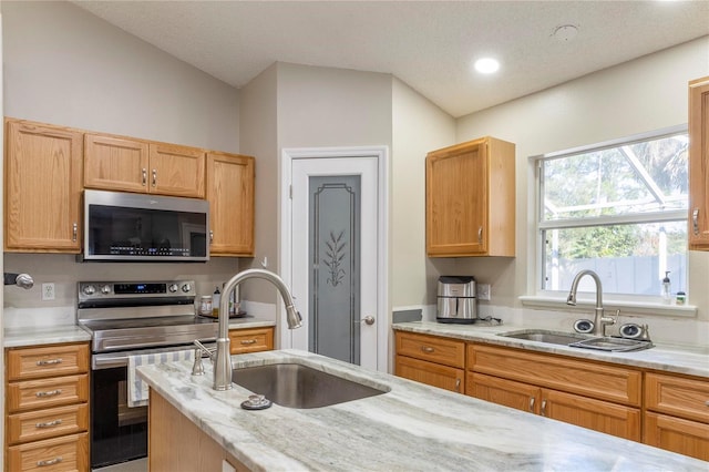 kitchen with a textured ceiling, sink, light stone countertops, and stainless steel appliances