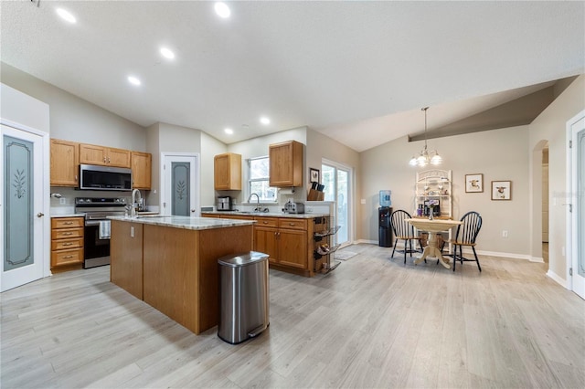 kitchen with pendant lighting, a center island, lofted ceiling, light hardwood / wood-style floors, and stainless steel appliances