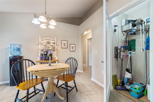 dining space with a chandelier, light hardwood / wood-style floors, and lofted ceiling