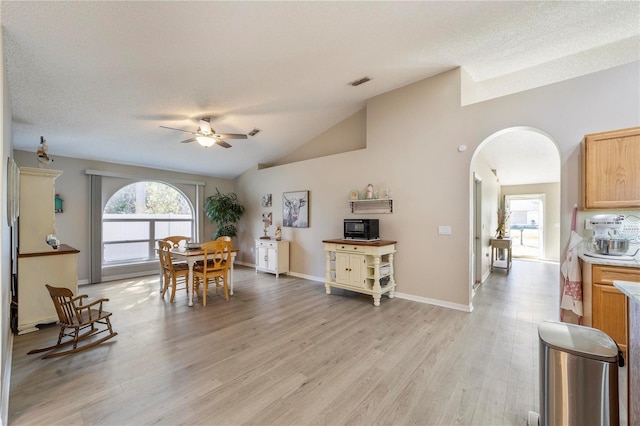 dining area with a textured ceiling, ceiling fan, light hardwood / wood-style floors, and vaulted ceiling