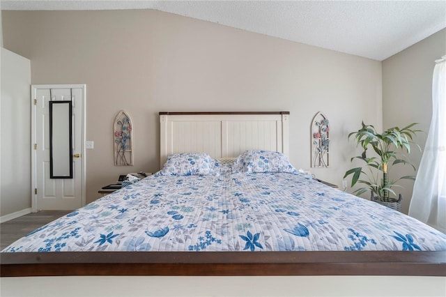 bedroom featuring hardwood / wood-style floors, a textured ceiling, and vaulted ceiling