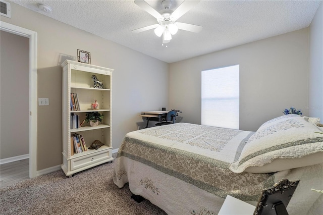 bedroom with ceiling fan, carpet floors, and a textured ceiling