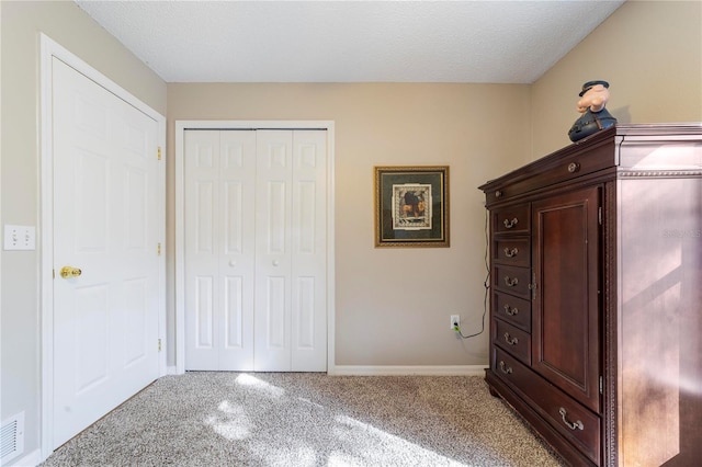 unfurnished bedroom featuring a textured ceiling, light carpet, and a closet