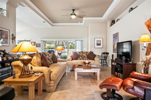 living room with ceiling fan, light tile patterned floors, a high ceiling, and a tray ceiling