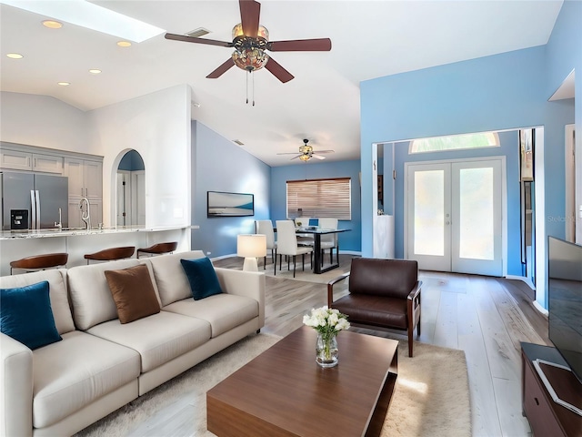 living room featuring french doors, ceiling fan, sink, high vaulted ceiling, and light hardwood / wood-style flooring