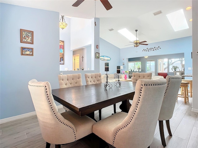 dining area featuring vaulted ceiling with skylight, ceiling fan, and light hardwood / wood-style floors