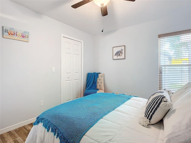 bedroom with multiple windows, ceiling fan, a closet, and hardwood / wood-style flooring