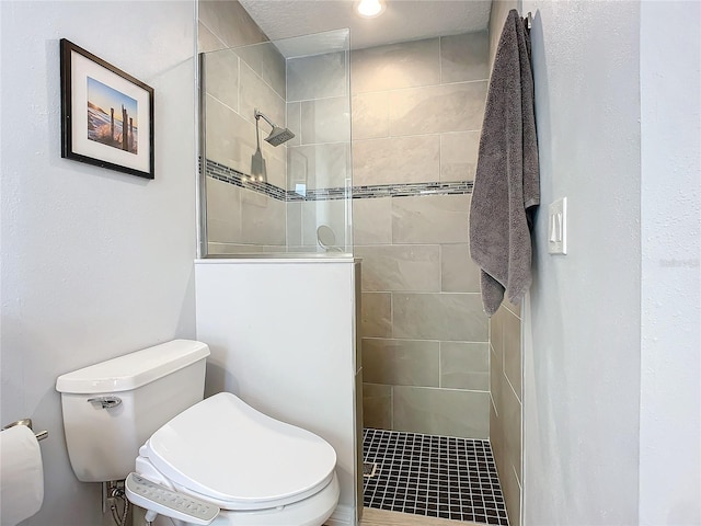 bathroom with a tile shower and toilet