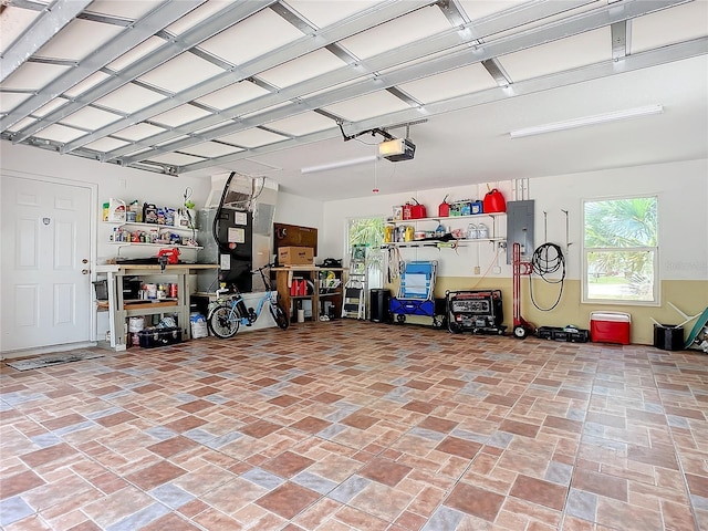 garage featuring electric panel, a garage door opener, and heating unit