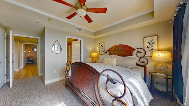 carpeted bedroom featuring ceiling fan, a raised ceiling, and ornamental molding