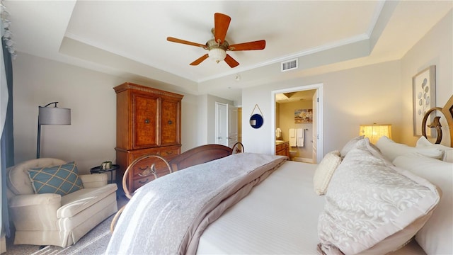 bedroom with a raised ceiling, ensuite bath, ceiling fan, and crown molding