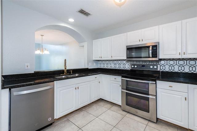 kitchen featuring tasteful backsplash, sink, light tile patterned floors, stainless steel appliances, and white cabinets