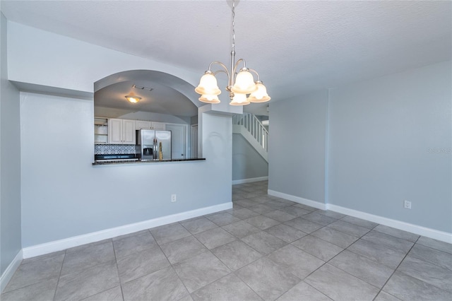 unfurnished dining area with a textured ceiling, a chandelier, and light tile patterned flooring