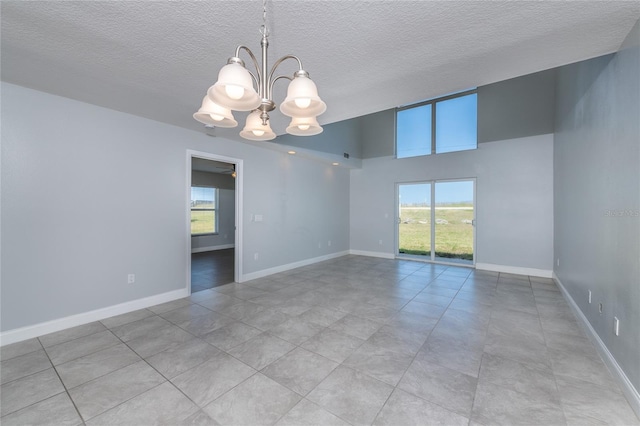 unfurnished room featuring a textured ceiling, light tile patterned floors, and ceiling fan with notable chandelier