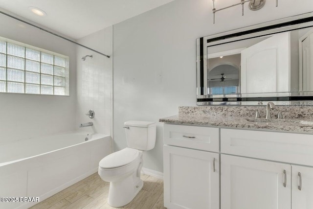 full bathroom featuring ceiling fan, vanity, toilet, tiled shower / bath combo, and wood-type flooring