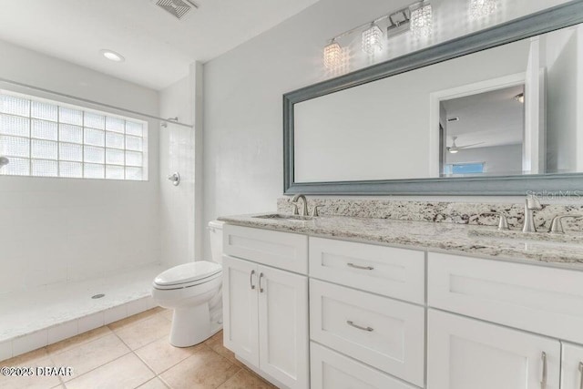 bathroom featuring toilet, a tile shower, tile patterned floors, and vanity