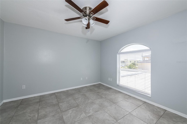 empty room featuring ceiling fan, plenty of natural light, and light tile patterned floors