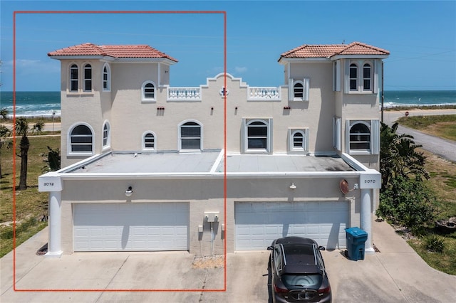 view of front of property featuring a garage, a water view, and a beach view