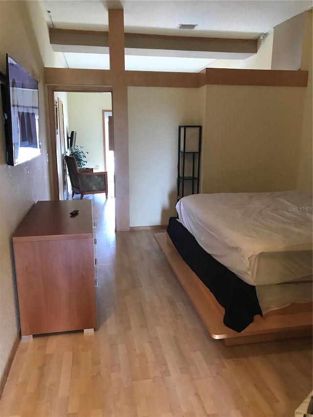 bedroom with beam ceiling and light hardwood / wood-style floors