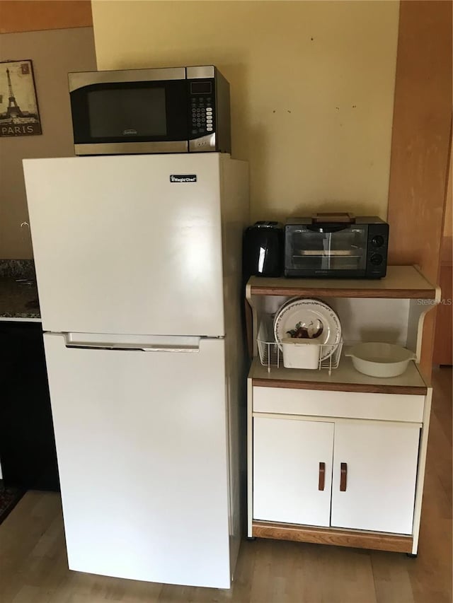 kitchen featuring white cabinets, white refrigerator, and light hardwood / wood-style floors