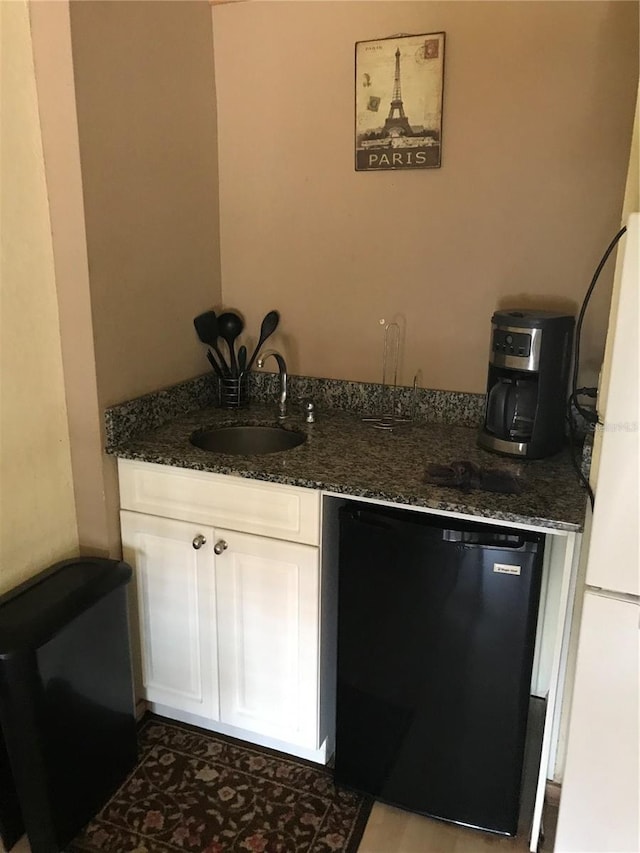 kitchen with sink, white refrigerator, dark stone counters, fridge, and white cabinets