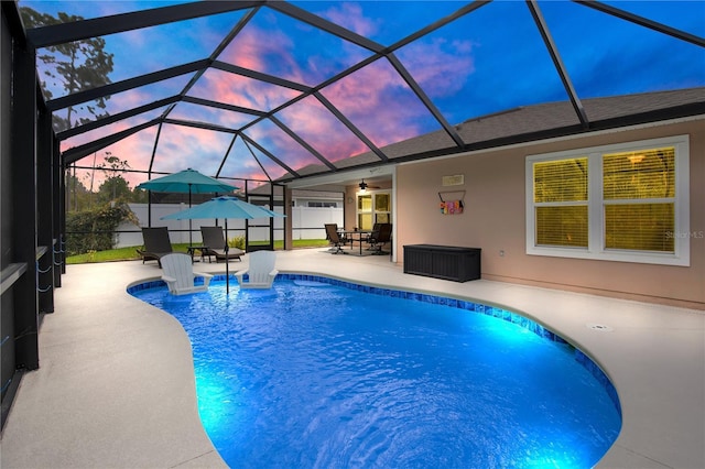 pool at dusk with a patio area, a lanai, and ceiling fan