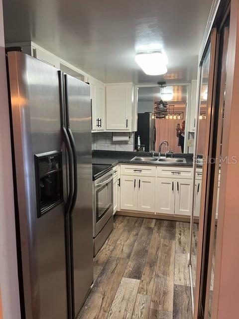 kitchen with appliances with stainless steel finishes, tasteful backsplash, sink, white cabinets, and dark hardwood / wood-style floors