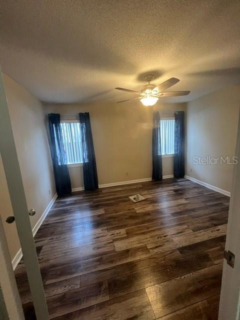 unfurnished room featuring a textured ceiling, dark hardwood / wood-style flooring, and ceiling fan