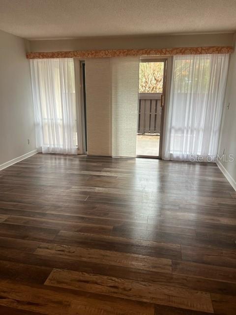 empty room featuring plenty of natural light and dark hardwood / wood-style floors