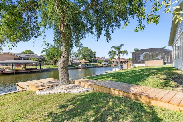 dock area with glass enclosure, a yard, and a water view