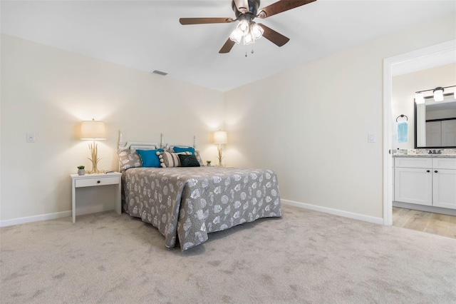 bedroom with ceiling fan, light carpet, and ensuite bath