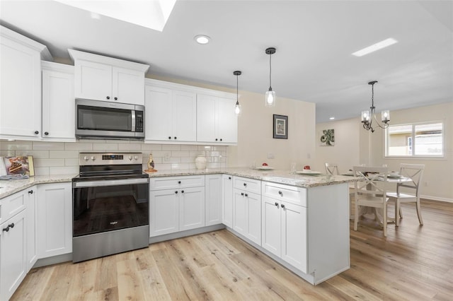 kitchen with kitchen peninsula, white cabinetry, hanging light fixtures, and appliances with stainless steel finishes