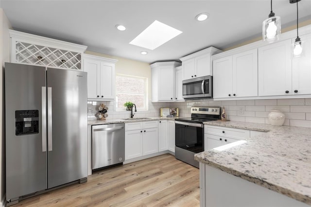 kitchen featuring sink, hanging light fixtures, a skylight, white cabinetry, and stainless steel appliances