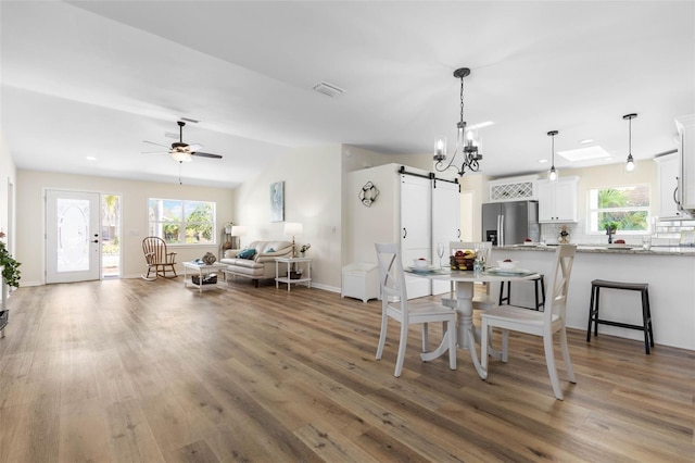 dining space with ceiling fan with notable chandelier, dark wood-type flooring, and a wealth of natural light