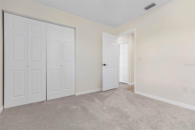 unfurnished bedroom featuring light colored carpet and a closet