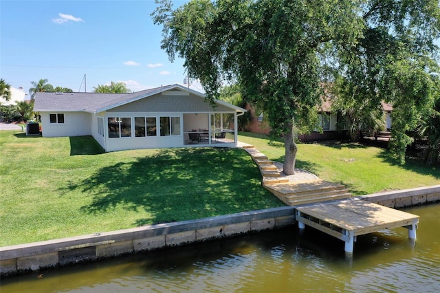 back of house with a water view, a patio area, and a lawn