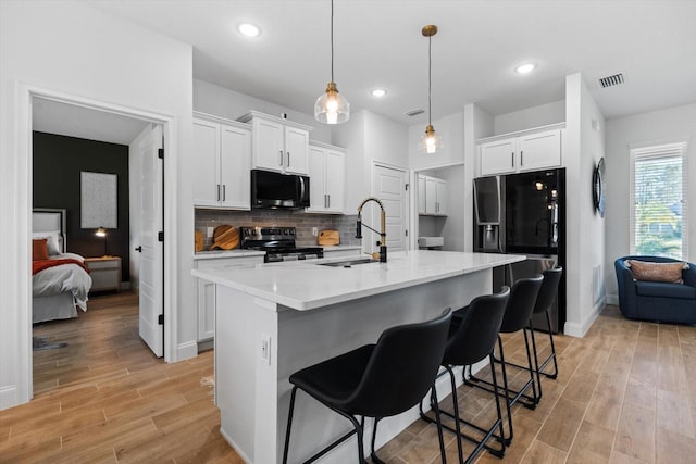 kitchen with white cabinets, black fridge with ice dispenser, sink, and electric stove