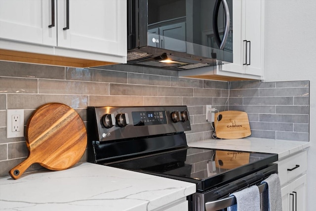 kitchen with light stone countertops, backsplash, white cabinets, and black electric range oven