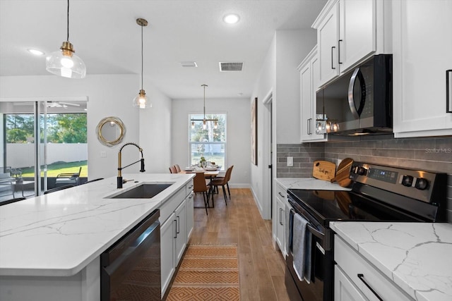 kitchen featuring sink, stainless steel appliances, tasteful backsplash, a center island with sink, and white cabinets