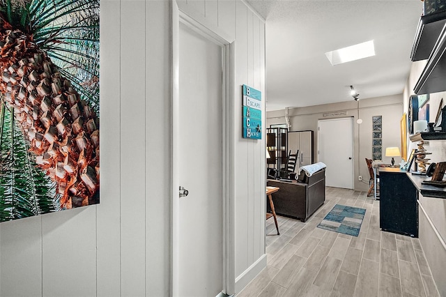 hall with a skylight and light hardwood / wood-style flooring