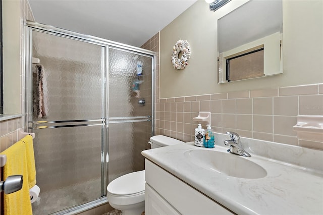 bathroom with vanity, toilet, walk in shower, and tile walls