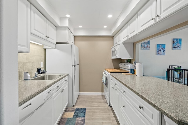 kitchen featuring white appliances, sink, light wood-type flooring, tasteful backsplash, and white cabinetry