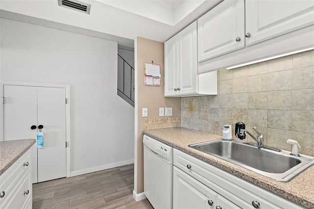 kitchen with white dishwasher, decorative backsplash, white cabinetry, and sink