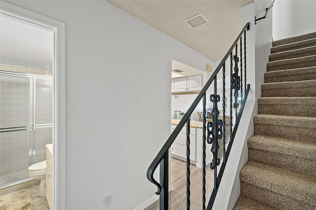 staircase with a textured ceiling and hardwood / wood-style flooring