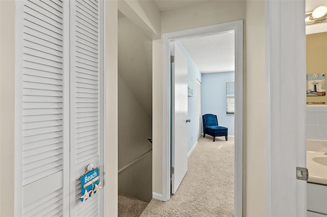 corridor with a textured ceiling and light colored carpet