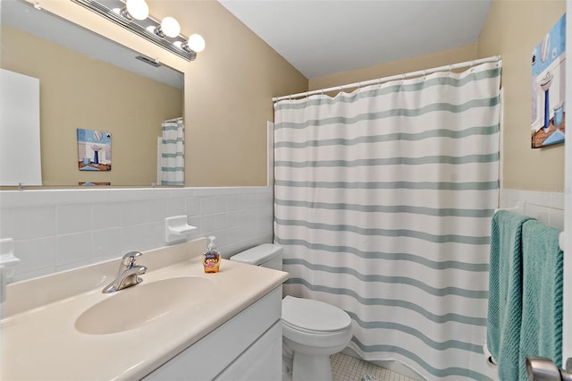 bathroom with walk in shower, tile patterned floors, toilet, vanity, and tile walls