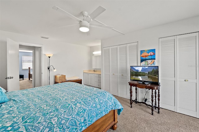 bedroom with light carpet, two closets, and ceiling fan