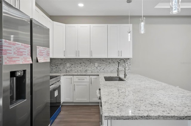 kitchen with appliances with stainless steel finishes, decorative light fixtures, white cabinetry, and sink