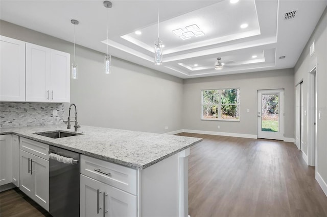 kitchen with ceiling fan, dishwasher, sink, white cabinetry, and a tray ceiling